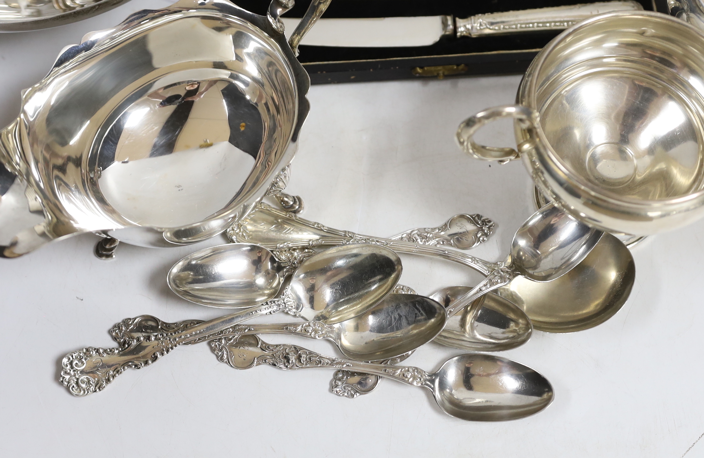 A small collection of silver including a sauceboat, two handled shallow bowl, five teaspoons and a commemorative spoon, together with a sterling cream jug and sugar bowl, sterling flatware and set of four pepperettes, to